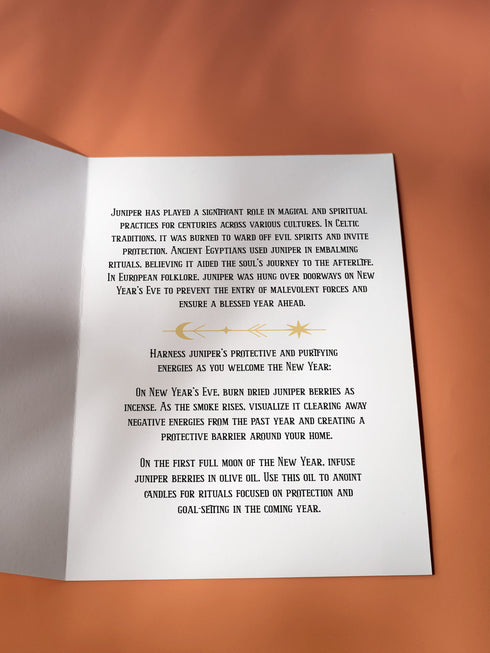 Juniper-themed holiday ritual card featuring a gold-stylized juniper branch with celestial accents on the front and an inside message detailing juniper's historical significance in magical practices, along with instructions for New Year's Eve and Full Moon rituals focused on protection and purification.